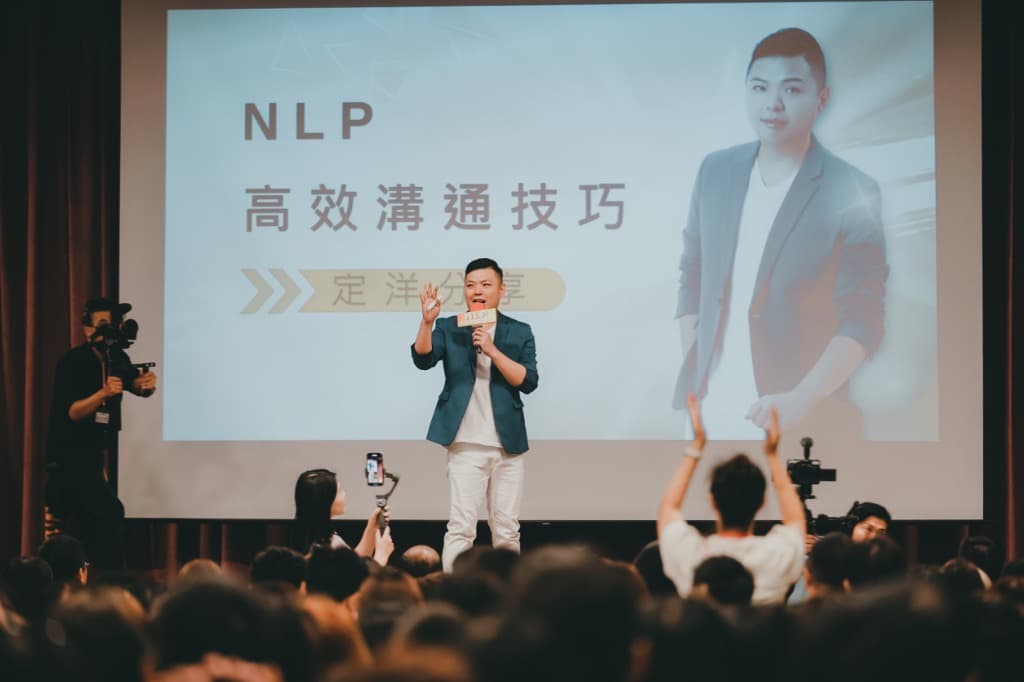 定洋在台上分享 NLP 高效溝通技巧,台下學員舉手回應